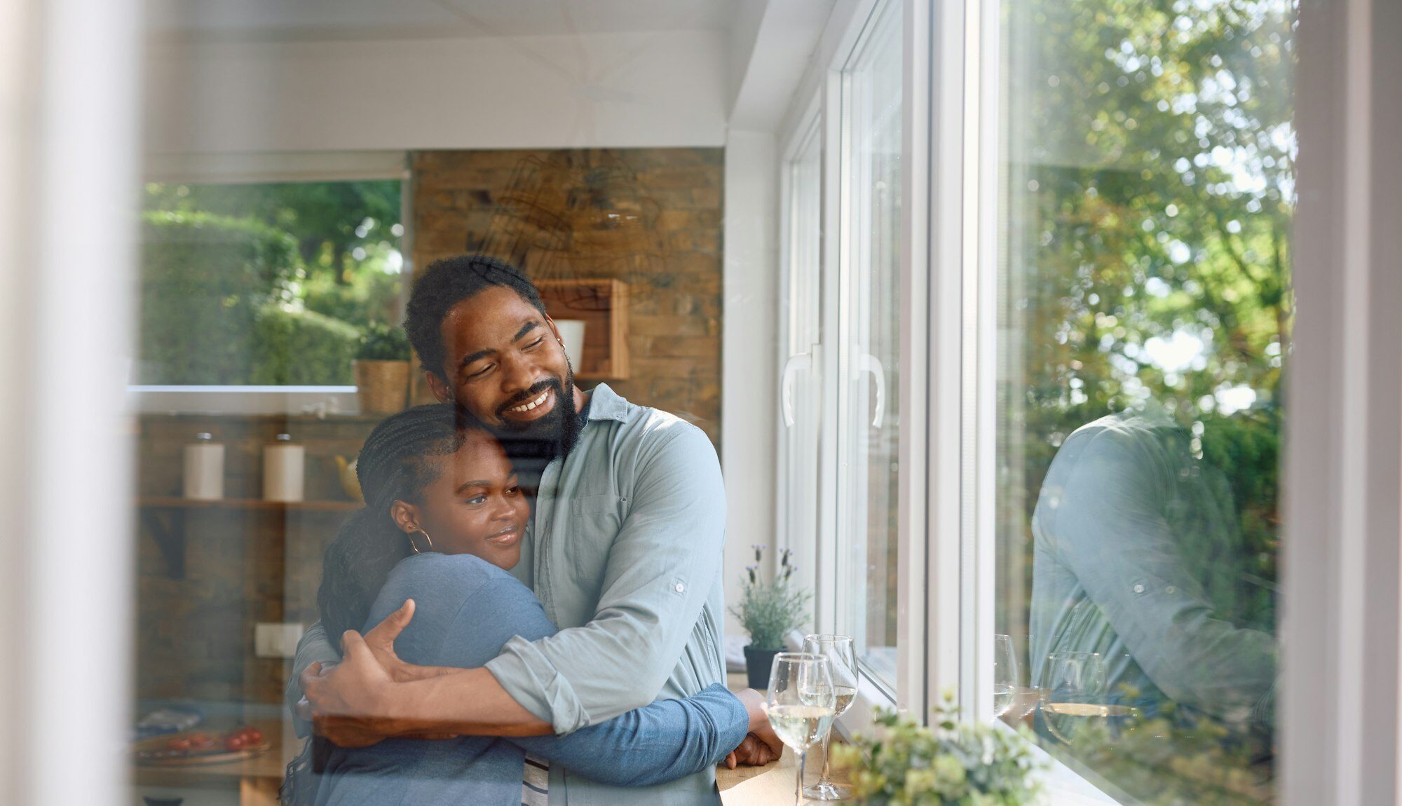 Embraced African American couple by the window at home.